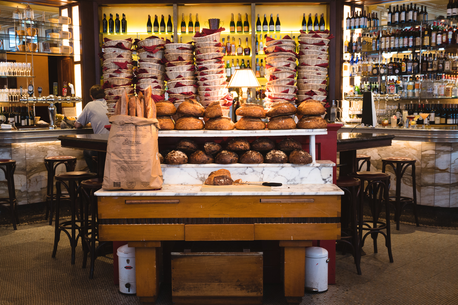 Bread table display - bag of baguettes, dark circular loaves stacked, light circular loaves stacked, baskets stacked